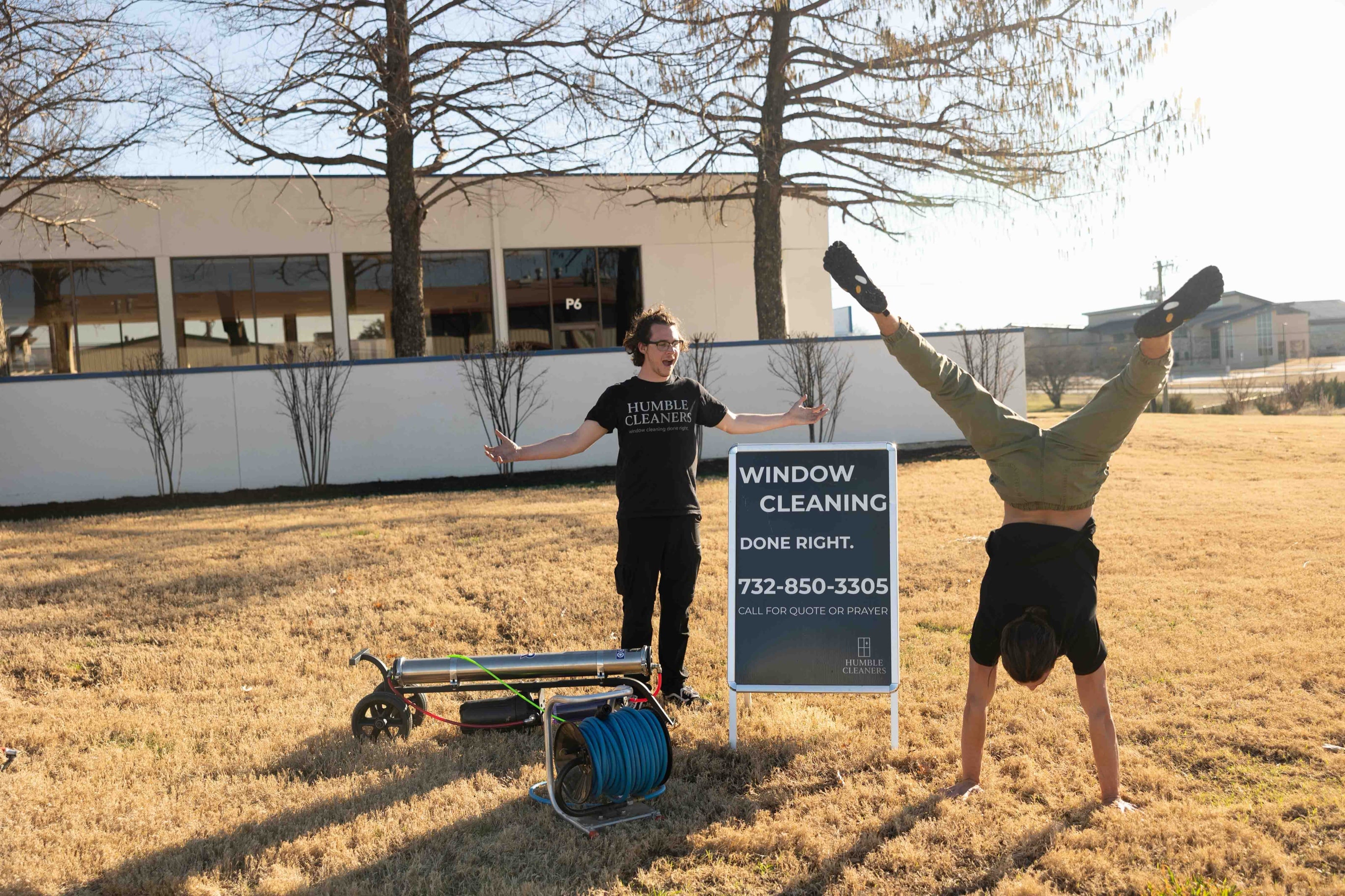 Two crew members goofing off beside the company yard sign