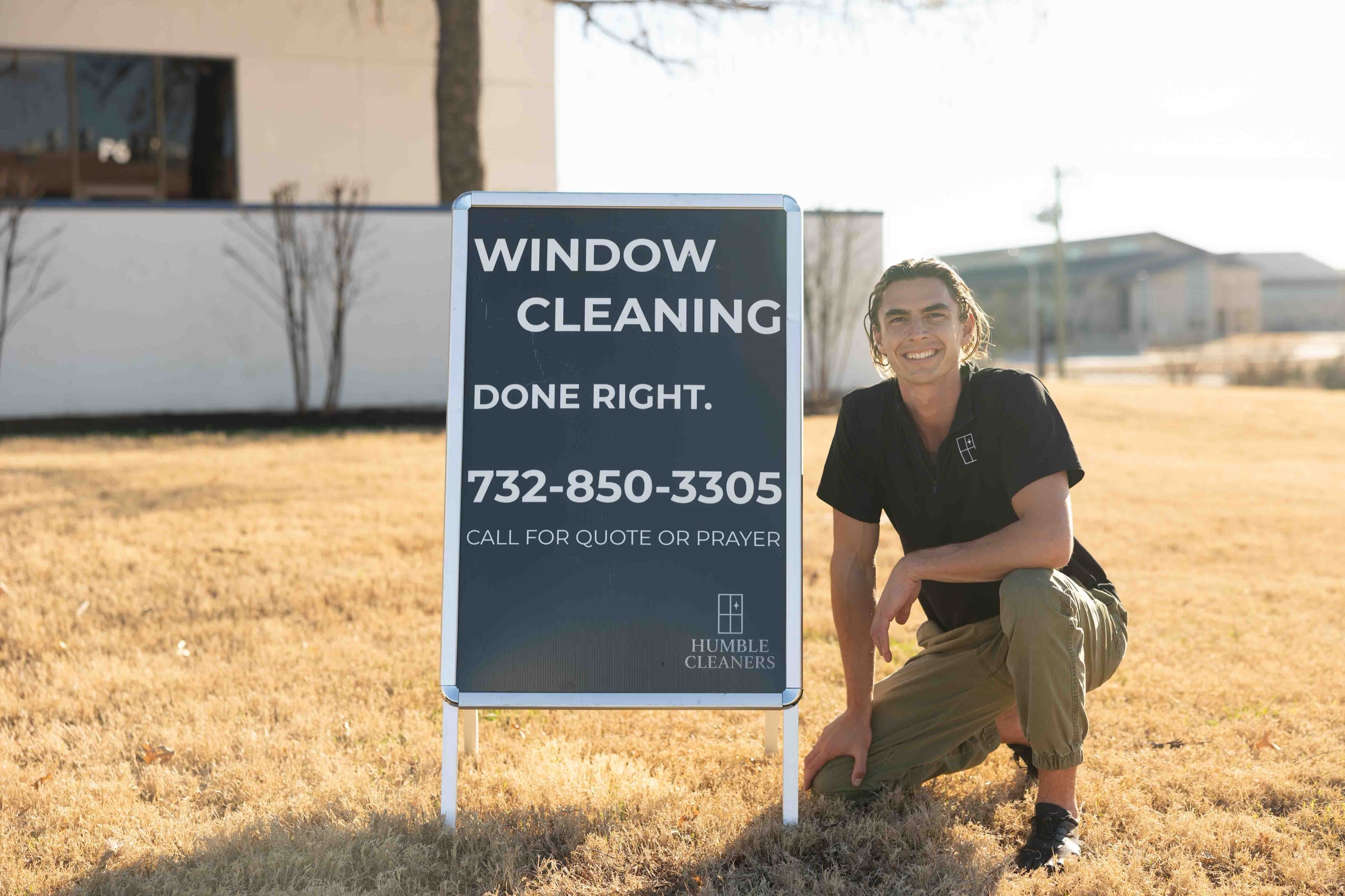 A crew member kneeling beside the company yard sign