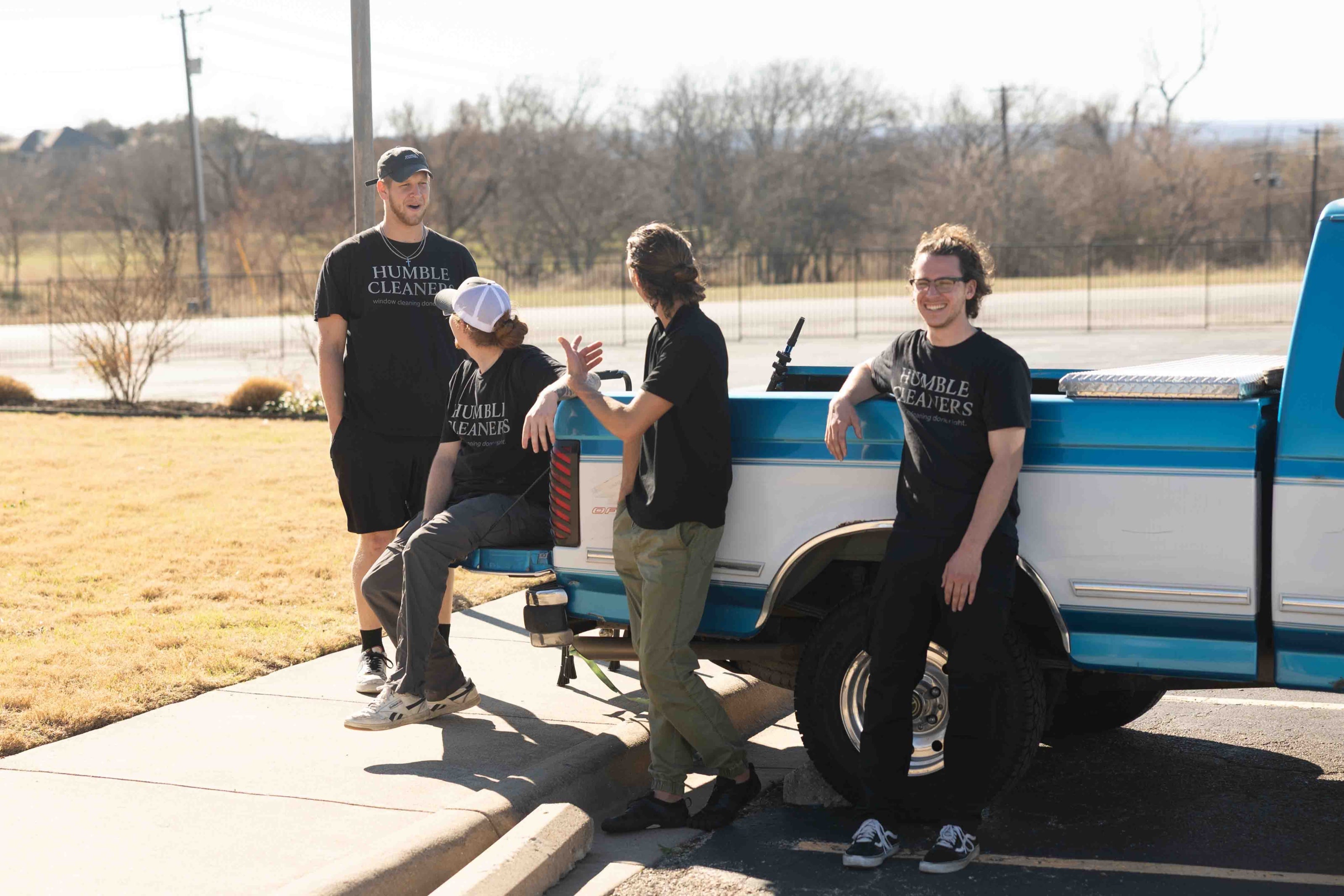 The Humble Cleaners team laughing together at the tailgate of their blue and white pickup truck